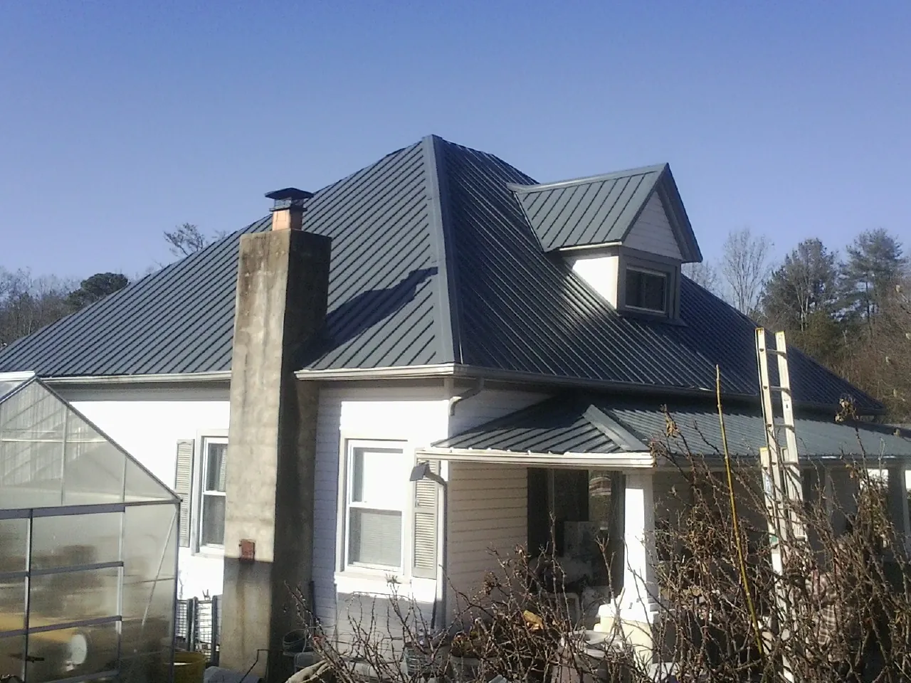 Dark blue standing seam metal roof on a white farmhouse with dormer — Slate & Tile Roof Repair by Roofing Brothers in Gwynedd Valley