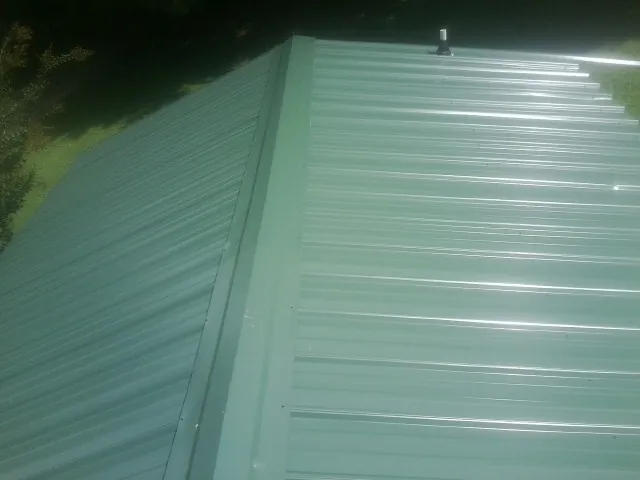 New green metal panels meeting at the ridge of a roof — Flat Roof Repair work by our crew in Gwynedd Valley