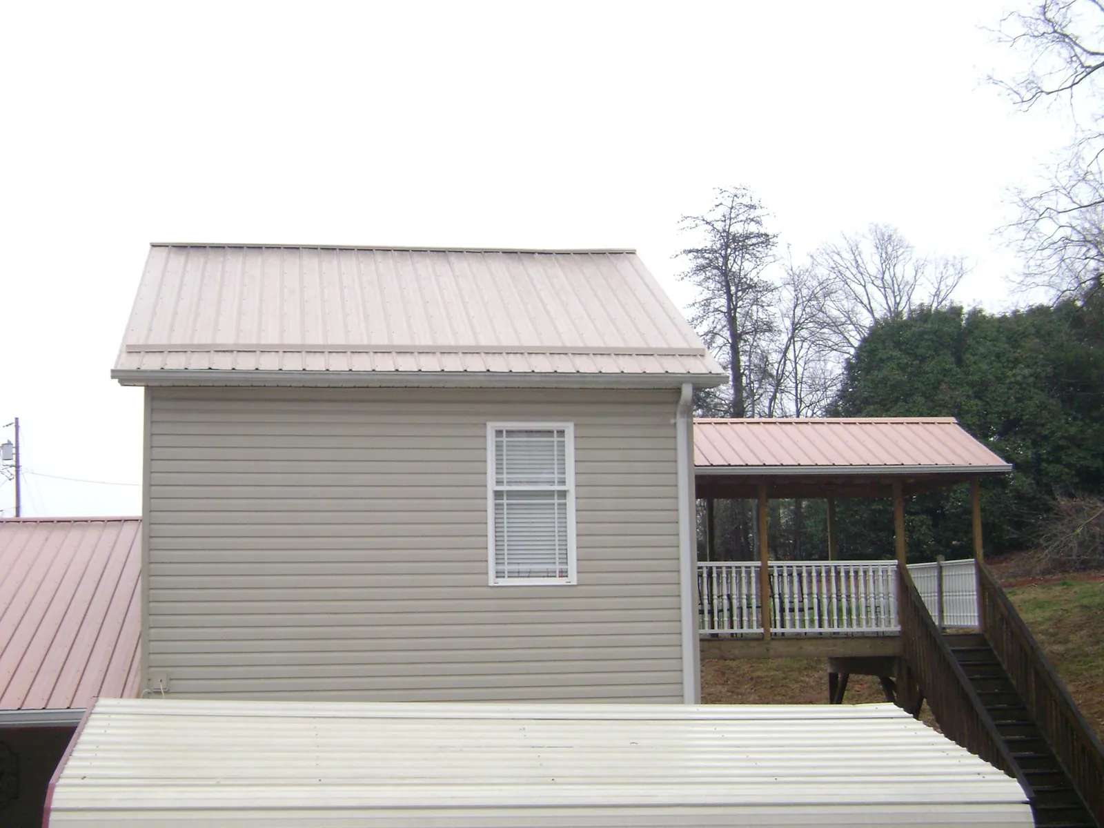 Tan metal roofs on a two story addition and attached porch, from a Roof Replacement job in Gwynedd Valley
