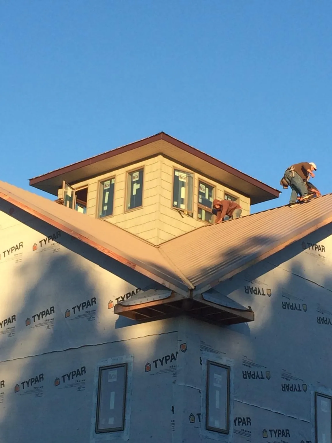 Roofers working around a rooftop cupola on a new metal roof at sunset — Roof Waterproofing in Gwynedd Valley by Roofing Brothers